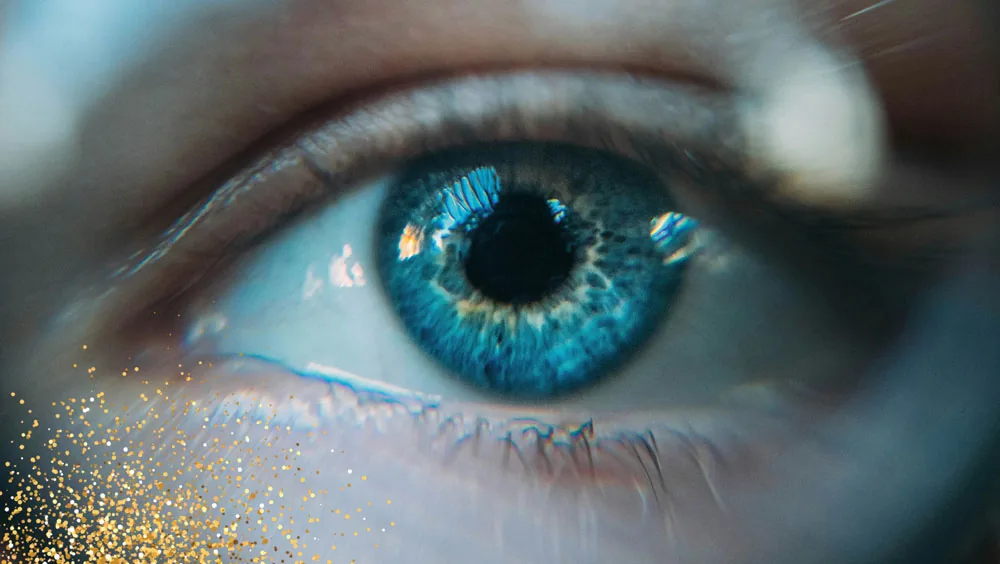 Nahaufnahme eines blauen Auges mit goldenem Glitzer