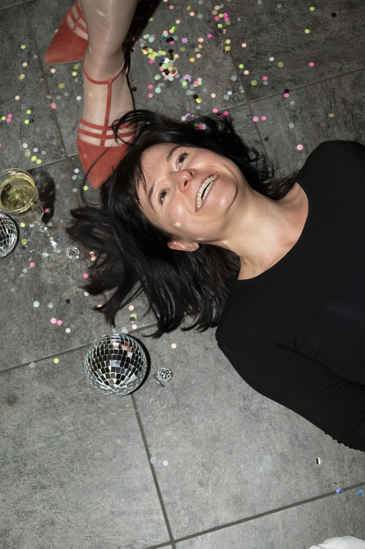 Anne von Magische Marken liegt lachend zwischen Konfetti und einer Discokugel auf dem Boden