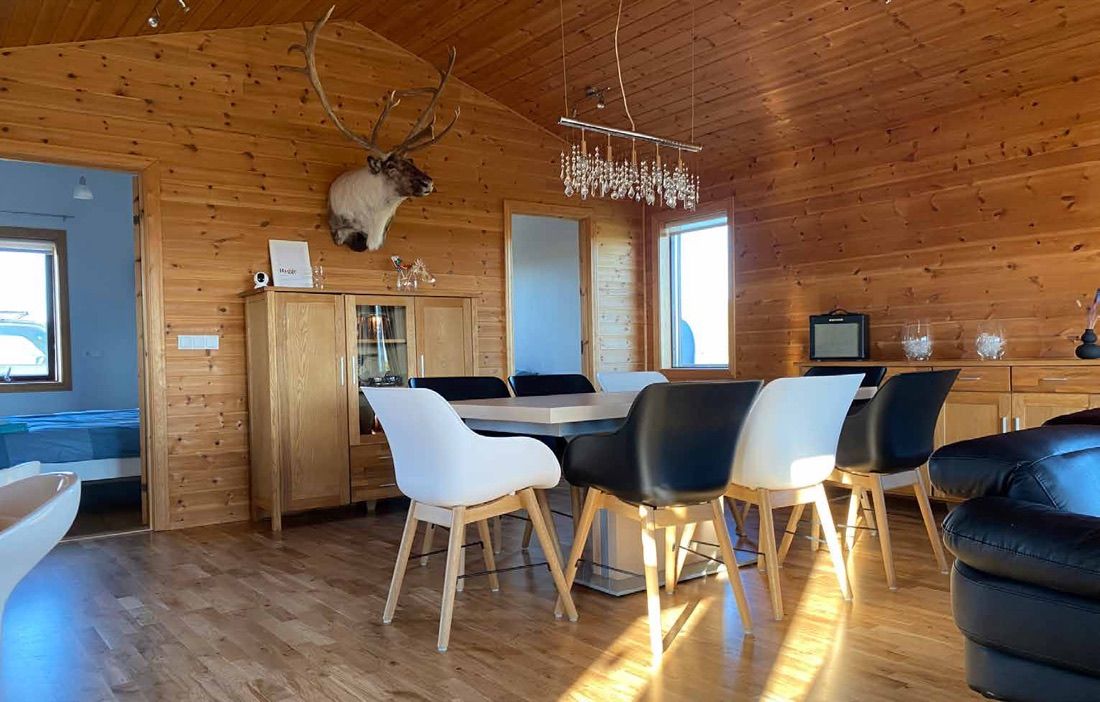Der offene Wohn- und Essraum des Hauses mit langem Tisch und Blick in die Küche