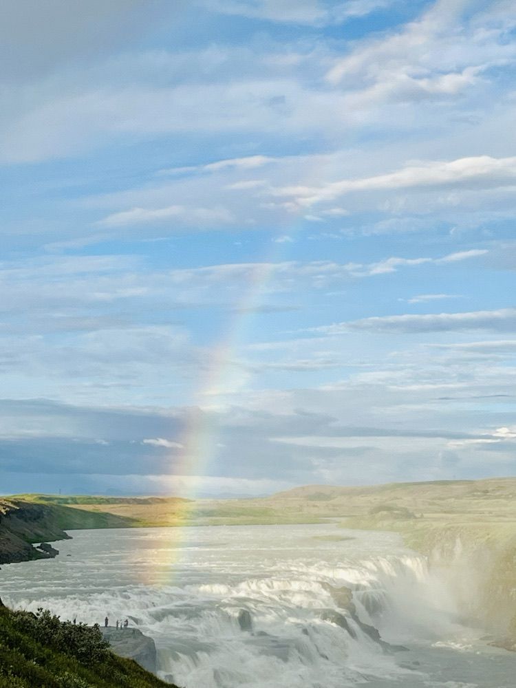 Ein Regenbogen steht senkrecht in der Gischt über den Stufen des Wasserfalls Gullfoss
