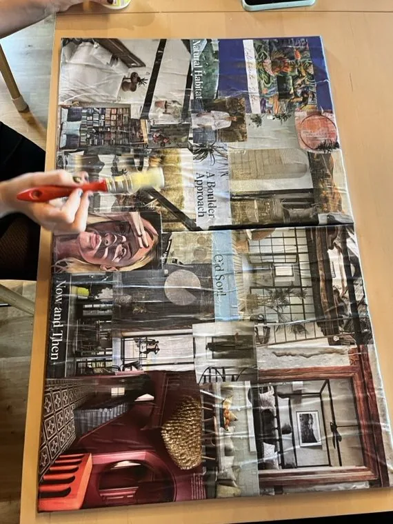 Eine Hand mit Marker über einer entstehenden Bildcollage aus ausgeschnittenen Fotos und Schriftzügen