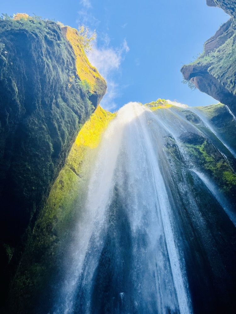 Der Wasserfall Gljúfrabúi fällt in eine enge, moosbewachsene Schlucht, von unten fotografiert